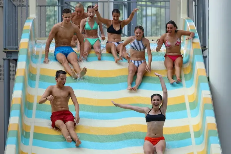 Fiatalok a többsávos családi csúszda tetején az Aqua Palotában